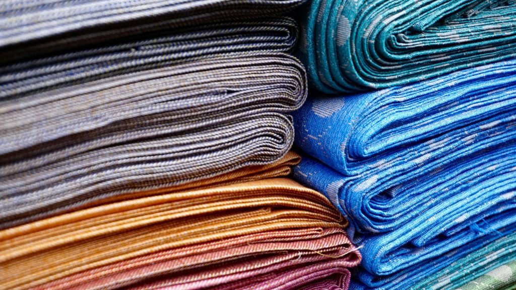pile of folded fabrics in various colors including blue and orange