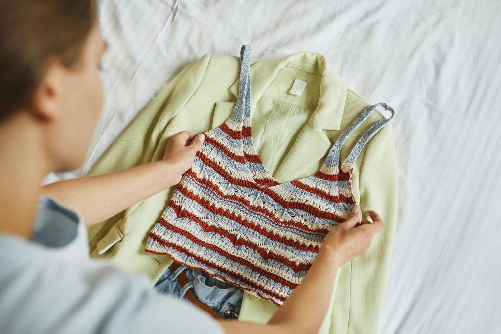 person laying outfit on bed with a light green blazer and red, white, and blue crochet tank top