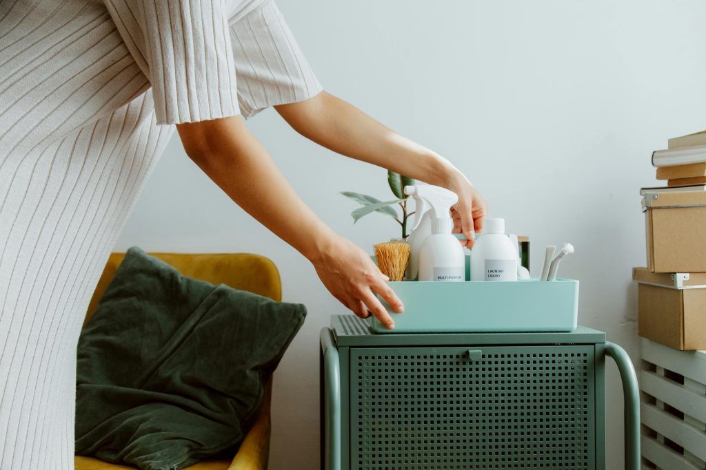 Personal holding a storage container of bath products on top of a green cabinet